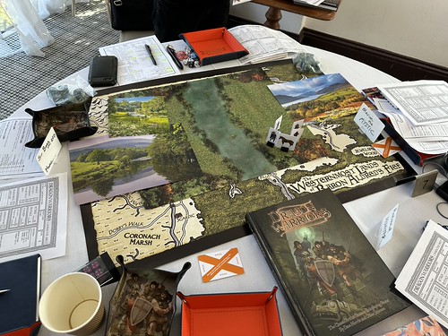 The table during 'A Box of Old Bones' - maps, photos, character standees and the Dragon Warriors rule book.