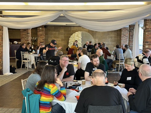 Furnace XX (2025) - a photograph of the main 'mess hall' gaming space with lots of people playing and enjoying themselves around tables full of characters sheets, dice and dice trays, books, drinks and snacks.